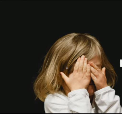 Petite fille se cache le visage derrière ses mains