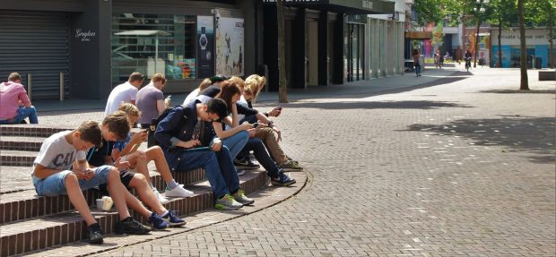une groupe d'adolescents assis la tête dans leur smartphone ou I-phone